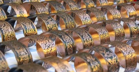 Engraved copper cuff bracelets with ornate traditional patterns displayed i.. Stock Photos