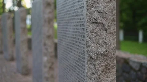 Engraved stone monuments stand in a garden, surrounded by green grass and trees. 스톡 동영상 344670148