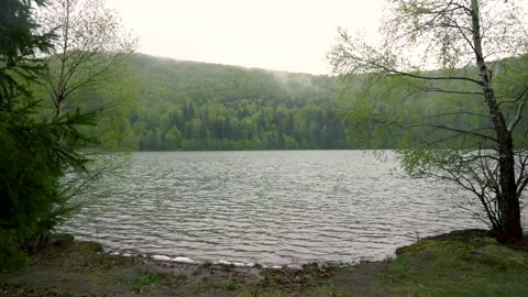 Enigmatic lonely man sitting on bench on lake shore in the mountain forest. Stock Footage 150593432