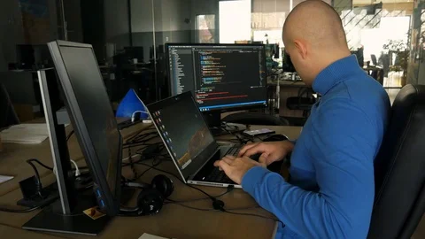 Enjoe work and looking on phone. The programmer works at a computer in an empty  Stock Footage