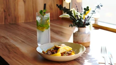 Enjoy a Delicious Meal Accompanied by a Refreshing Drink in a Cozy and Inviting Stock Footage 311874134