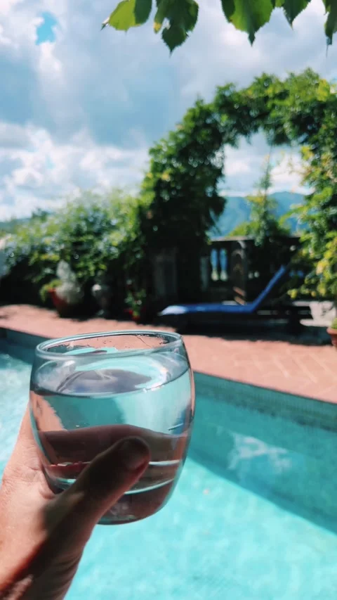 Enjoy a Refreshing Poolside Escape with a Cool Glass in Hand to Relax and Unwind Video stock 283981615