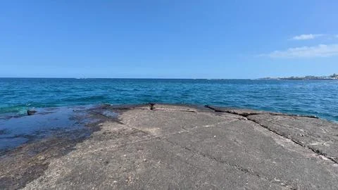 Enjoy Tranquil Ocean Waves lapping against Rocky Shoreline under a Clear Blue Stock Photos