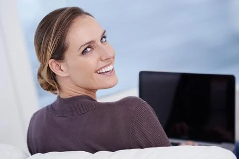 Enjoying broadband connectivity. A young woman smiling as she works on her Stock Photos