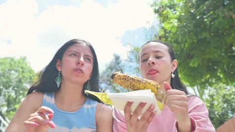Enjoying charred grilled corn on the cob outdoors 動画素材 334884773