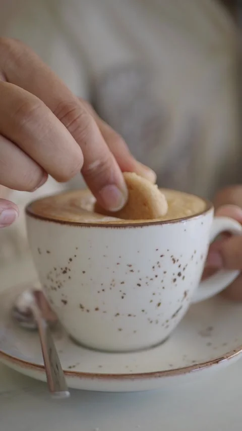 Enjoying coffee with a cookie dip in a cozy cafe Stock Footage 341455417
