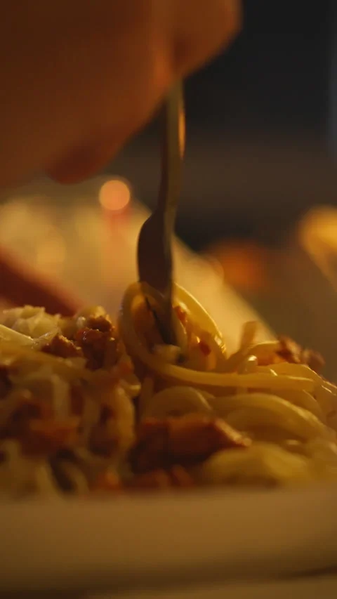 Enjoying a cozy candlelit dinner while twirling spaghetti with a fork Stock Footage 331571342