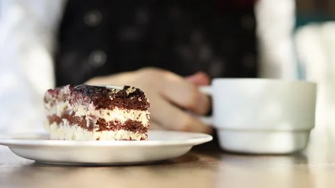 Enjoying a decadent slice of cake with a warm cup of coffee in a cozy cafe Vidéo 295271387