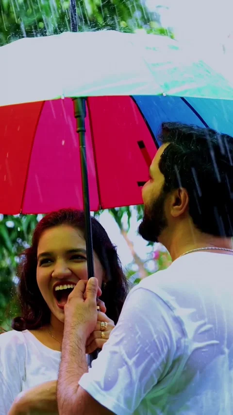Enjoying first rain shower, Indian couple having fun under umbrella in park Stock Footage 343163992