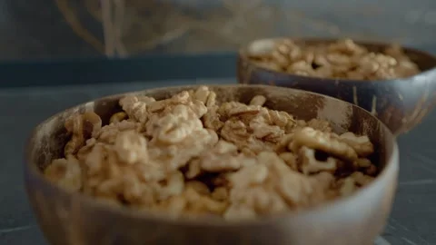 Enjoying fresh walnut kernels in rustic bowls on a stylish table Stock Footage 327580557