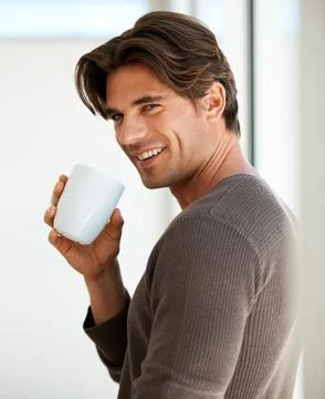 Enjoying his first cup of java. A handsome young man standing at home and Stock Photos