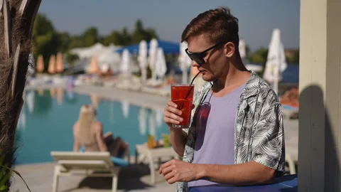 Enjoying a leisurely time at the poolside while sipping a delightful and refresh Stock Footage 305732107