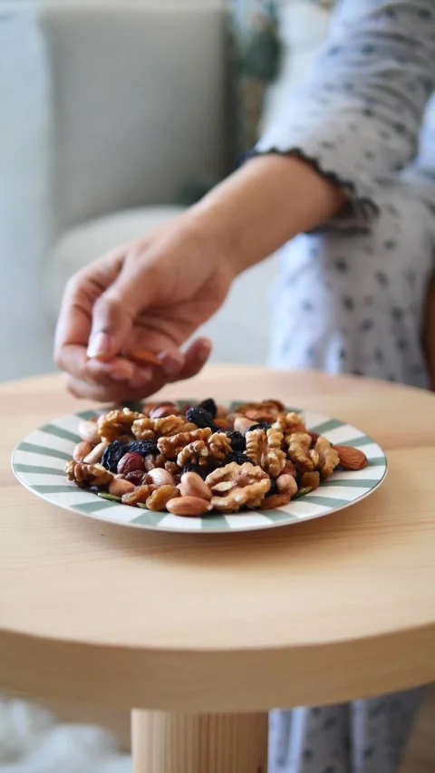 Enjoying mixed nuts on a table in a cozy space Stock Footage 336422858