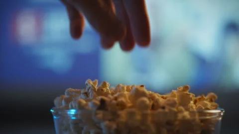 Enjoying popcorn while watching a movie at home during movie night Stock Footage 303662408