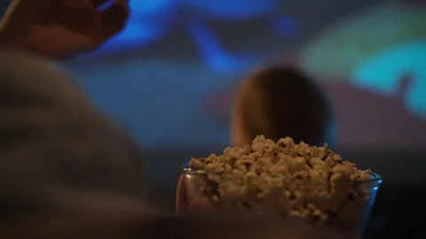 Enjoying popcorn while watching a movie at home on a cozy evening Stock Footage 323766894