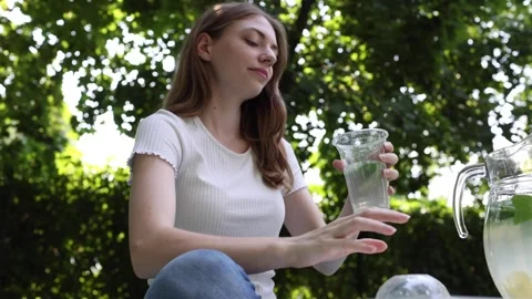 Enjoying a refreshing drink while relaxing in a sunny garden Stock Footage 297361091