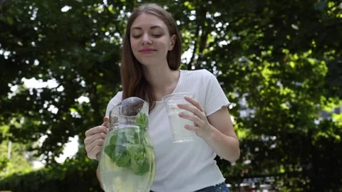 Enjoying refreshing lemonade while relaxing outdoors in the park Stock Footage 297361618