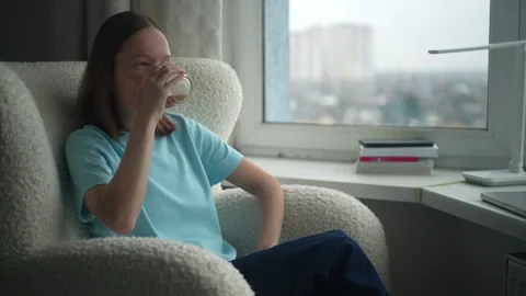 Enjoying a relaxing moment at home while sipping a drink near the window on a Stock Footage 322164584