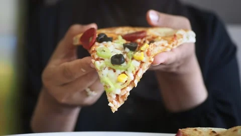 Enjoying a slice of pizza with toppings in hand Stock Footage 339755268