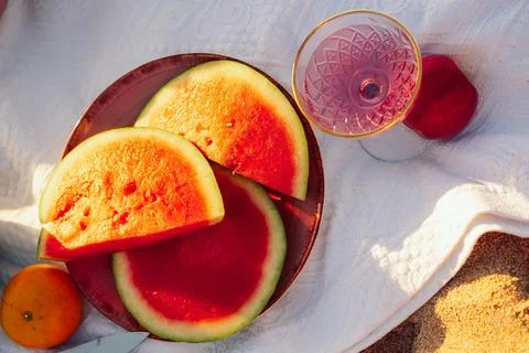 Enjoying  sunny beach scene with fruit and  drink at sunset near water.  grou Stock Photos