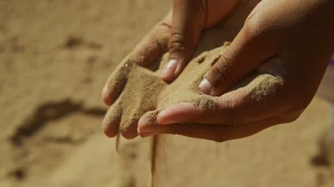 Enjoying a sunny day at the beach while feeling the warm sand slip through Stock-Footage 308302444
