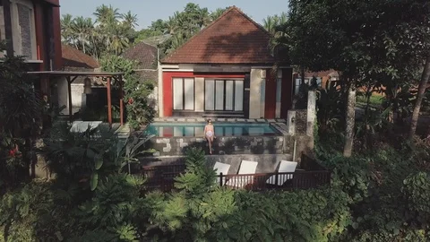 Enjoying the time next to the pool in the villa in jungle aerial footage Stock Footage 100273660