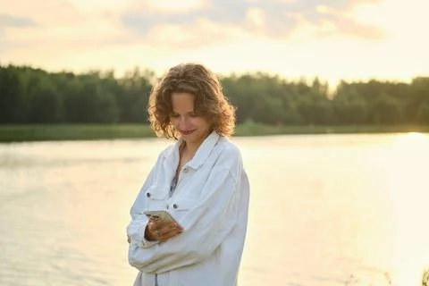 Enjoying a warm day at the lake while checking messages on a smartphone Stock Photos
