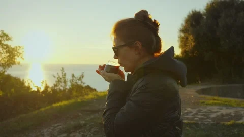 Enjoying a warm drink while admiring a breathtaking coastal sunset Stock Footage 296188621