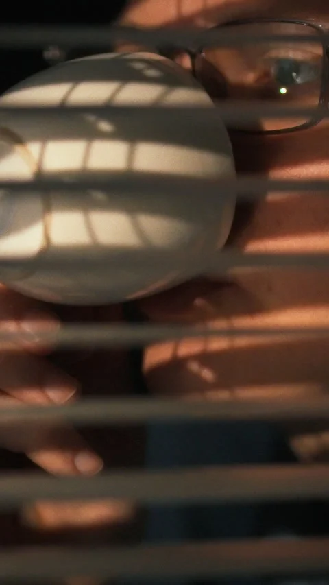 Enjoying a warm drink while peering through blinds during a tranquil evening Stock Footage 331571970