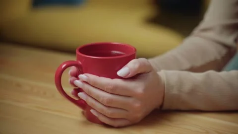 Enjoying a warm drink while relaxing indoors on a cozy afternoon with soft Stock Footage 303768308