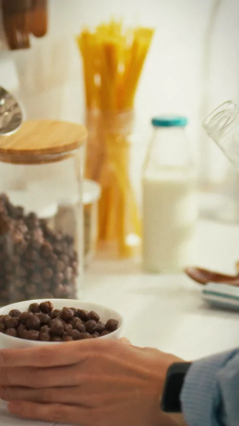 Enjoying a wholesome breakfast with cereal and milk in a cozy kitchen Stock Footage 331571953