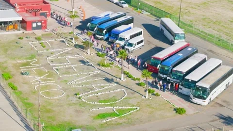 Ensenada, Mexico – June 25, 2026: Tour buses and large stone city sign at port 動画素材 337629924
