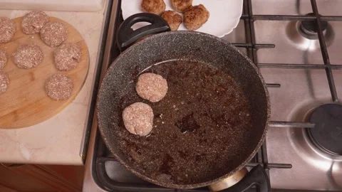 Ensuring uniform cooking by properly spacing burger rounds in pan Stock Footage 330023609