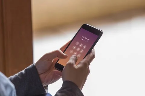 Enter Passcode concept. Hands holding smartphone while entering the passcode. Stock Photos