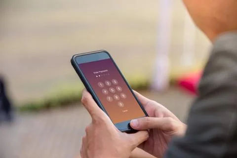 Enter Passcode concept. Man holding smartphone while entering the passcode. Stock Photos