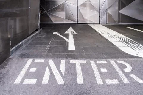 Enter text with two arrows painted on the floor of an underground parking ent Stock Photos