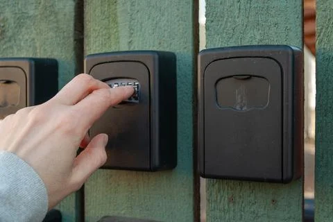 Entering code on outdoor key lock box system Stock Photos