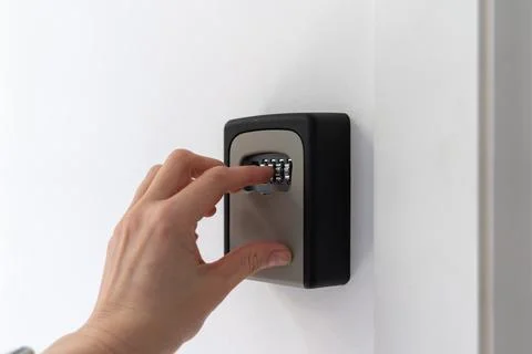 Entering code on wall mounted key lockbox for contactless check in Stock-Fotos