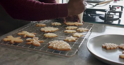 On entering frame, baker's hands are decorating leaf and fir cookies with icing Stock Footage 345035126