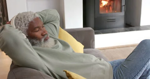 Entering frame senior man settling on gray couch with pillow, relaxing and Stock Footage 314030058