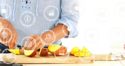Entering from left cook in light blue blouse, slicing mango on kitchen counter Stock Footage 331593301