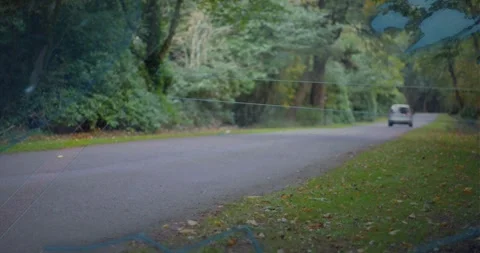Entering left, silver van moving right along tree-lined road, faint map overlay Video stock 333962793