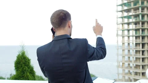 Enterprising architect talking on the phone while standing next to new building Video stock 55358175