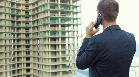 Enterprising architect talking on the phone while standing next to new building Stock Footage 55358252