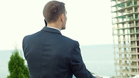 Enterprising architect talking on the phone while standing next to new building Stock Footage 55358272