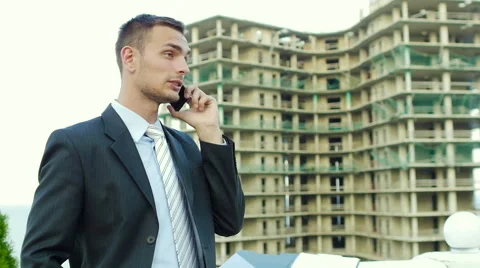 Enterprising architect talking on the phone while standing next to new building Stock Footage 55358331
