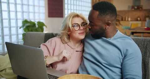 Entertainment time of pleasant mixed race couple resting on couch using laptop Stock Footage 123671704
