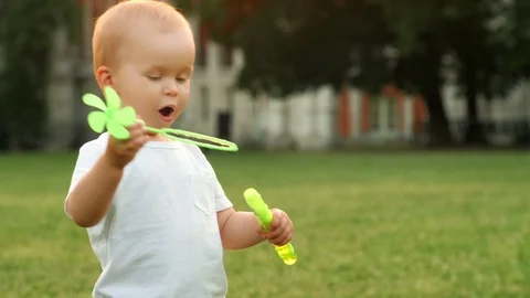 Enthusiastic active boy blowing soap bubble having fun at backyard nature Stock Footage 113206357