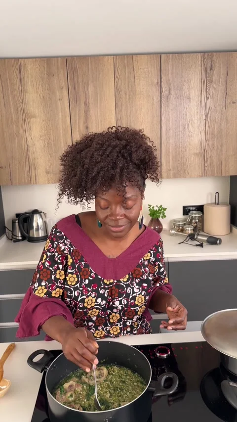 Enthusiastic African woman dancing while preparing Okra Soup Stock Footage 302826717