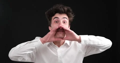 Enthusiastic Caucasian man shouting into an imaginary megaphone on a black Stock Footage 248530644